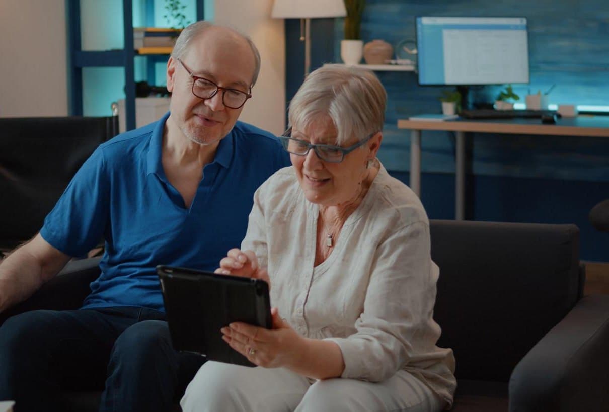 An older couple at home looking at a tablet together